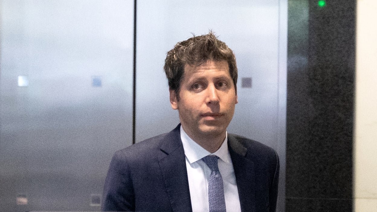Sam Altman in a suit in front of an elevator