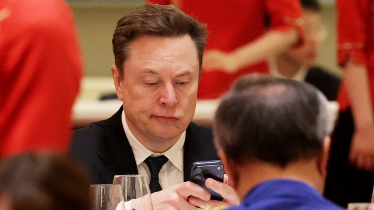 Elon Musk looks downcast at his phone
